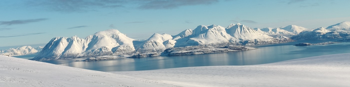 Snötäckta fjäll vid en fjord i Lyngen, Norge